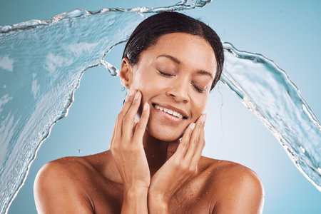 Woman, skincare and beauty for clean hydration, cosmetics or hygiene against a blue studio background. Female model in relax with water splash for facial cleanse or care treatment for skin on mockupの写真素材