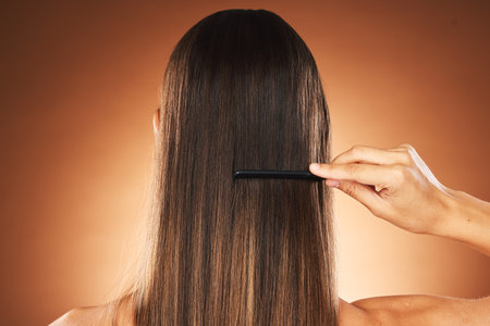 Beauty, hair care and comb for maintenace, combing and self care routine with growth, shine and repair shampoo on a gradient background. Back of female for health, wellness and hairstyle in studioの写真素材
