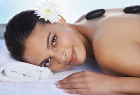 Hot stone massages feel fantastic. A beautiful woman receiving a hot stone massage.の写真素材