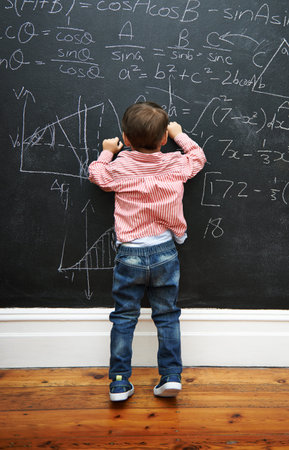 Challenge accepted. a young boy with a blackboard full of math equations.