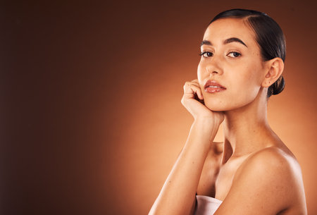 Cosmetics, skincare and young woman for wellness, heath and confident with brown studio background. Portrait, female and girl with makeup, natural beauty and organic facial for smooth and clear skin.の写真素材