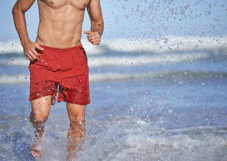 Running to save lives. a male lifeguard running through the water.の写真素材