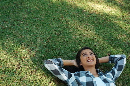 Daydreaming in the sun. A beautiful young woman lying on her back in the park.