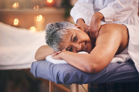 Spa, massage and senior woman on table with hands of therapist on back for happiness, health and wellness. Luxury, hospitality and body care for customer in retirement with physical therapy for peaceの写真素材