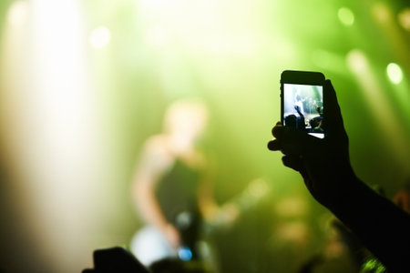 Capturing the moment. A person filming their favourite band with a camera phone.の写真素材