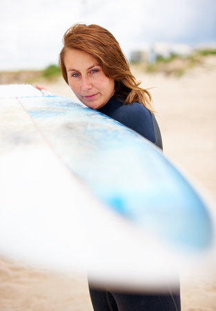 The ocean is my playground. A young female surfer holding her surfboard.の写真素材