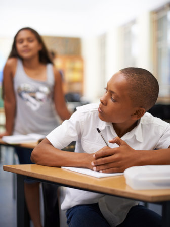 Stop copying me. A young boy writing a test while a classmate tries to copy.の写真素材