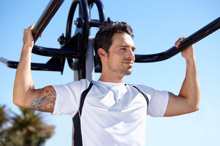 Hes constantly working to improve his fitness. A handsome young man working out outdoors.の写真素材