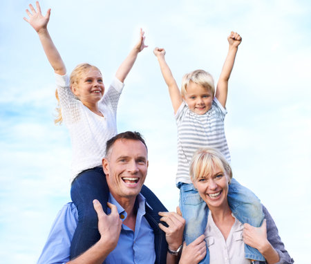 We love our family. Cropped view of two parents carrying their children on their shoulders outdoors.