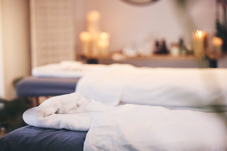 Spa, massage bed and blurred background with candles, bokeh and room for health, wellness and treatment. Physical therapy table, luxury resort or beauty salon for body care, relax or peace in Bangkokの写真素材