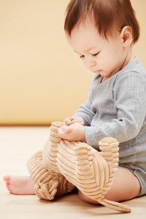Curious about his new toy...an adorable baby boy playing with a stuffed animal.