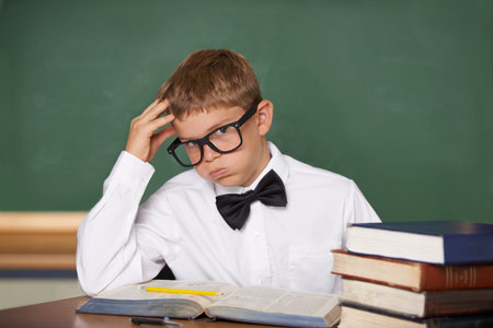 Not another pop-quiz. A young schoolboy in glasses and a bow-tie sighing wearily while looking at...