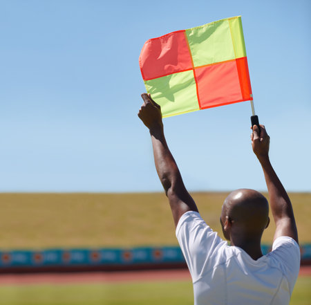 Signaling a foul. A linesman with a raised flag signaling a foul.の写真素材