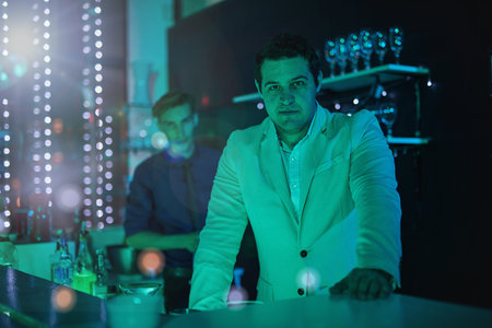 Club, drink and portrait of a bartender working at a party, happy hour and night club event. Lens flare, alcohol server and barman at a dark nightclub for drinks, work and entertainment lifestyleの写真素材