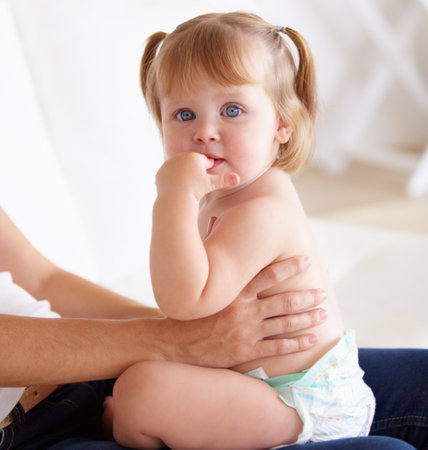 Sitting with Mom. A cute little girl sitting on her mothers lap.の写真素材