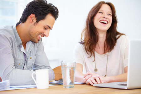 The lighter side of the working life. two colleagues having a friendly conversation while working...