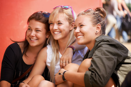 Capturing the good times. Three pretty girls smiling for a photograph while at a music festival.の写真素材