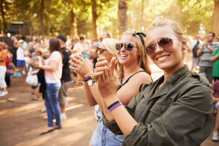 This is an epic festival. Two friends applauding an entertainment act at an outdoor festival.の写真素材