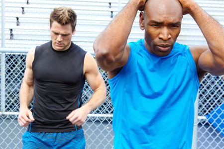 Warming up before the race. two male athletes wearing sports clothing and readying themselves for...