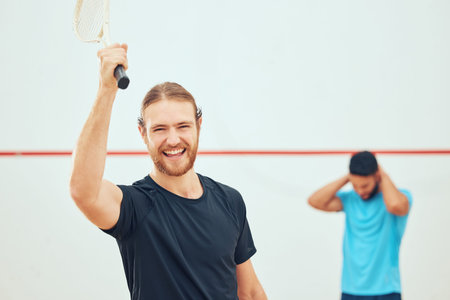 Young athletic squash player winning after playing opponent in competitive court game. Fit active...