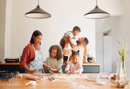 A happy mixed race family of five relaxing and cooking together. Loving black family being playful while baking together. Young couple bonding with their foster kids at home in a messy kitchenの写真素材