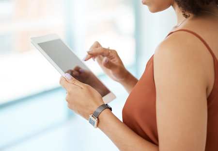 Unrecognizable woman holding and using a digital tablet at home. Unrecognizable woman using social media on a digital tablet at work.の写真素材