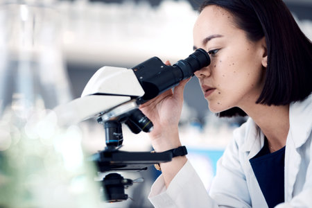 Microscope, scientist or woman with research, medical cure or check sample data in laboratory. Asian...