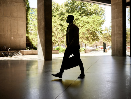 Silhouette of a businessman walking in a station on his way to work in the morning while carrying his bagの写真素材