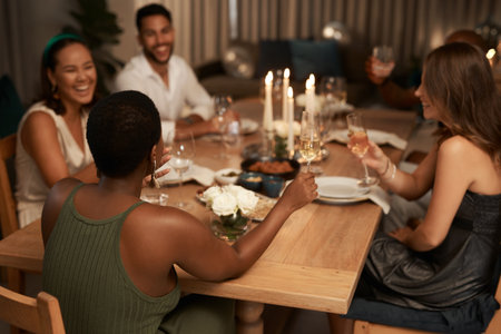Dinner, party and champagne toast with friends celebrating new year. Social event, celebration and happy group of people with wine glasses having fun, laughing and enjoying holiday time together.の写真素材