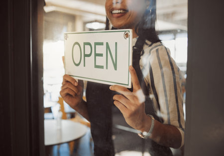 Closeup on hands of business owner hanging open sign. Businesswoman hanging signage in her store...