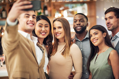 Group of friends, selfie and party for celebration, smile and bonding in restaurant. Diversity, young business people and corporate event for fun, relax and device to connect, social media and team.の写真素材