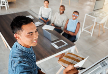 Group of diverse businesspeople having a meeting in an office at work. Young happy mixed race businessman smiling while writing an idea on a whiteboard in a boardroom with colleagues. Businesspeopleの写真素材