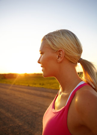 What a beautiful sunset. A beautiful young sportswoman looking at the sunset.