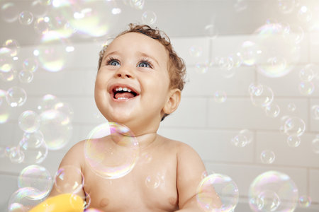 Your first breath took ours away. a baby having fun in a bath at home.の写真素材