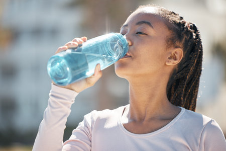 Drinking water, fitness and black woman in urban city with workout challenge for health, wellness...