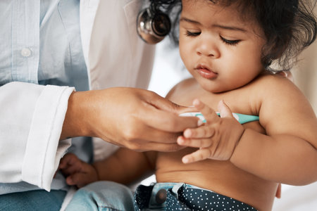Youre running a little warm. a little baby having her temperature taken at the doctors office.の写真素材