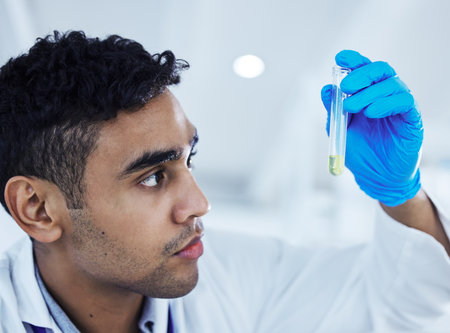 He wastes no time. a young male scientist analysing a test tube.の写真素材