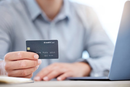 Spending from the business account. Closeup shot of an unrecognisable businessman using a laptop and credit card in an office.の写真素材