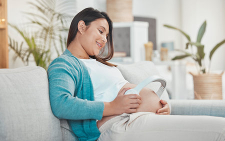 Pregnant, woman and stomach with headphones for music for her unborn baby while relaxing at home....