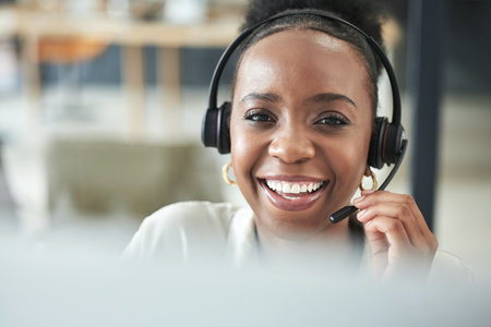 What can I do for you today. an attractive young call centre agent sitting alone in the office.の写真素材