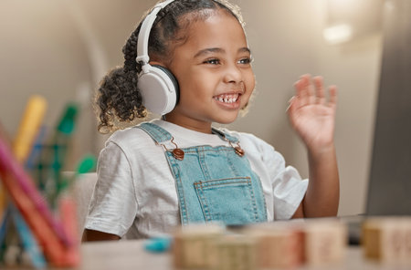Video call, headphones and child in e learning on laptop, home desk and hello for virtual class education, communication and listening. Audio, pc technology and kindergarten girl in language learningの写真素材