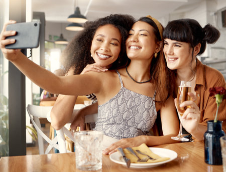 Spreading love no matter where they go. a group of young friends taking selfies together at a restaurant.の写真素材
