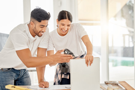 Go straight into the corner. a young couple standing together and using a power drill at home.の写真素材