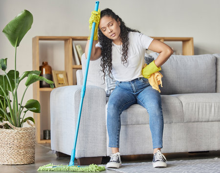 Cleaning, tired and mop with woman in living room for housekeeping, hygiene or disinfection. Pain, exhausted and fatigue with girl cleaner resting after domestic and tidy for dirt, bacteria or dustの写真素材