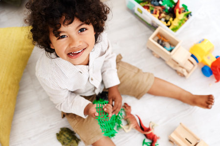 You can never have enough toys. Portrait of an adorable little boy sitting on the floor and playing with his toys at home.の写真素材