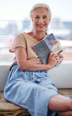 This book is very dear to my heart. Cropped portrait of an attractive senior woman reading a book while relaxing on her balcony at home.の写真素材