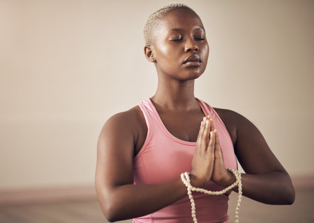 Focusing on my inner peace. an attractive young woman sitting indoors and using mala beads during her meditation routine.の写真素材