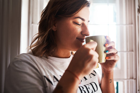 The smell of coffee takes all my worries away. a beautiful young woman having coffee at home.の写真素材