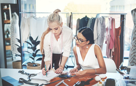 Were working together to create a masterpiece. two young fashion designers working together in a...