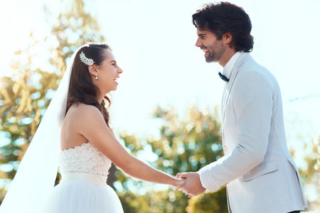 Married to happiness. an affectionate young newlywed couple smiling at each other while holding hands on their wedding day.の写真素材
